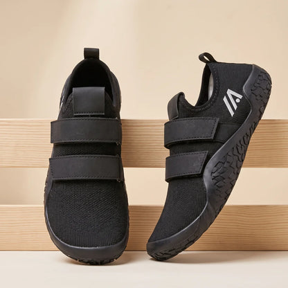 Alvidon KraftStep Schwarz – Trainingsschuhe für Kraft und Gym, an drei hellen Holzlatten gelehnt, Barfußschuhe für Damen und Herren